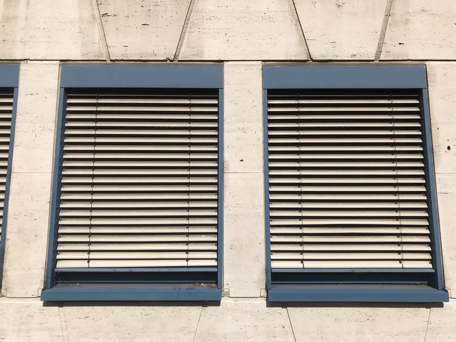 Stores à lamelles extérieurs à mi-hauteur sur la façade d'un immeuble